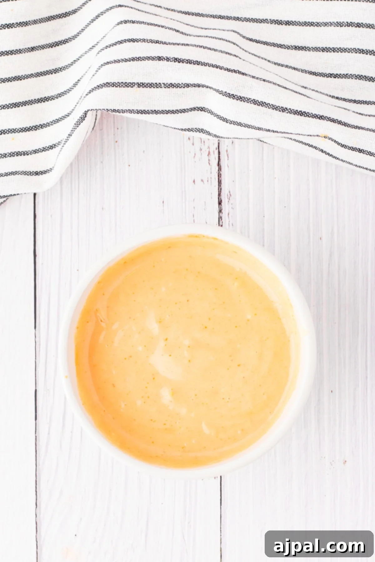 Ultimate Fry Dip 7 A small cup of vibrant orange French fry sauce sits elegantly on a clean white table, ready to be enjoyed.