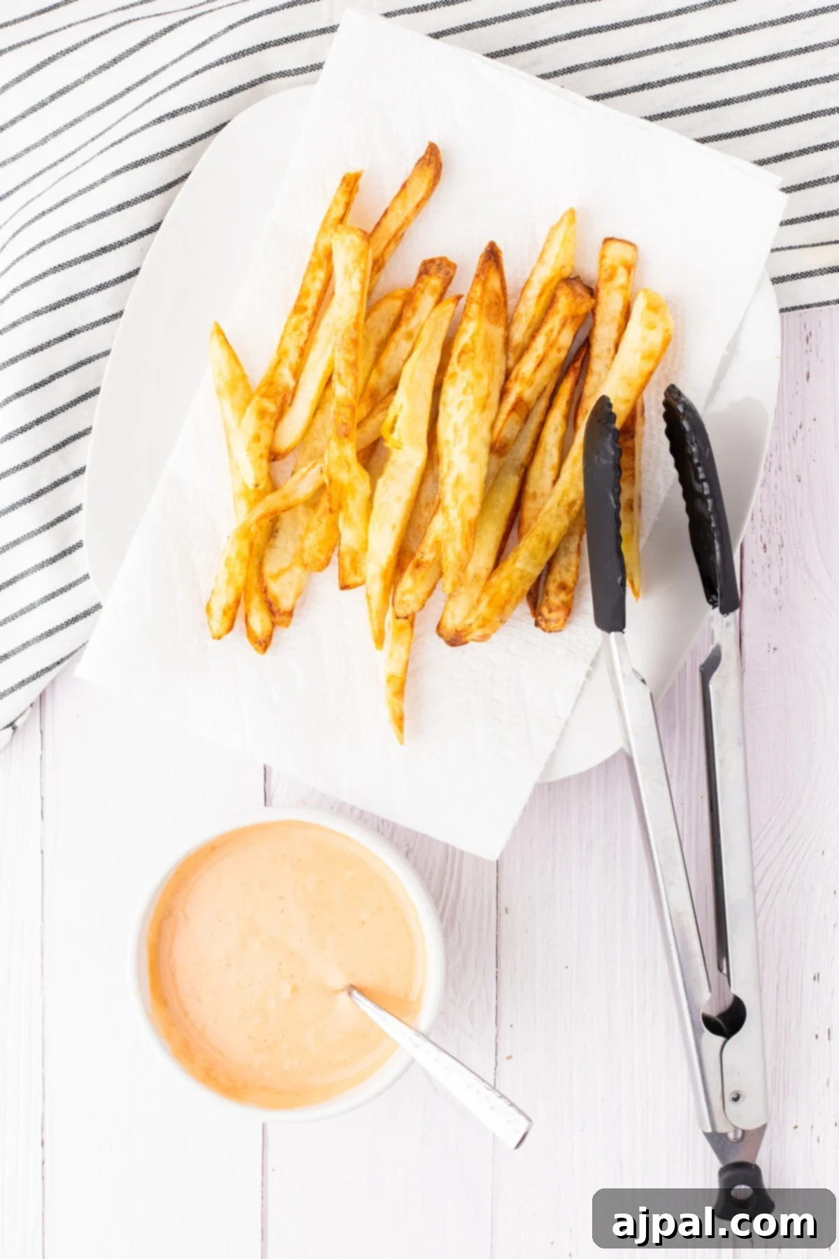 Ultimate Fry Dip 5 A plate of golden French fries next to a small white cup filled with our delectable homemade fry sauce, ready for dipping.