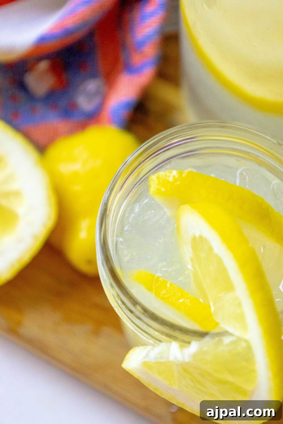 A rustic jar filled with homemade lemonade, adorned with a fresh lemon slice, sits against a soft-focus background, ready for a refreshing drink.