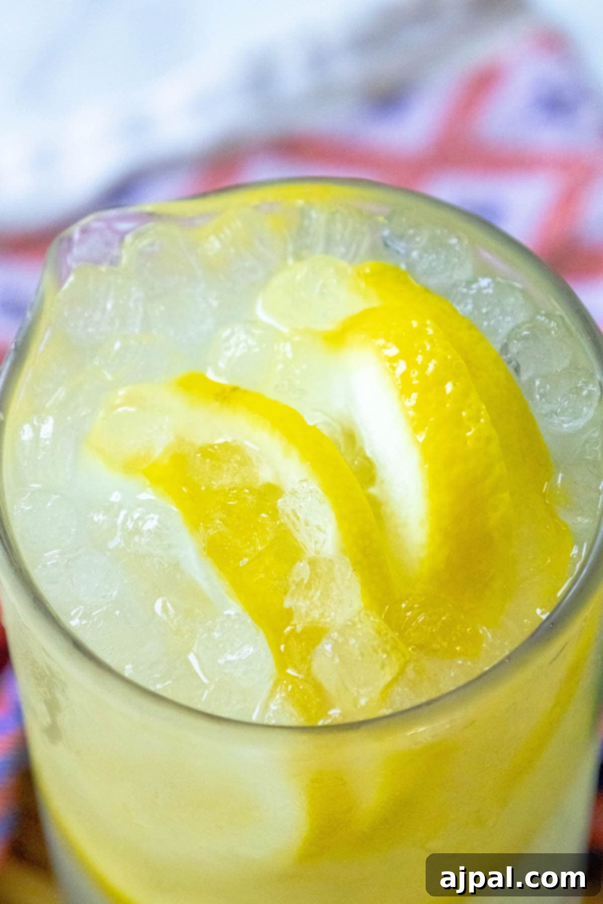 A refreshing glass of homemade lemonade, overflowing with ice and adorned with vibrant lemon slices, epitomizing a perfect summer drink.