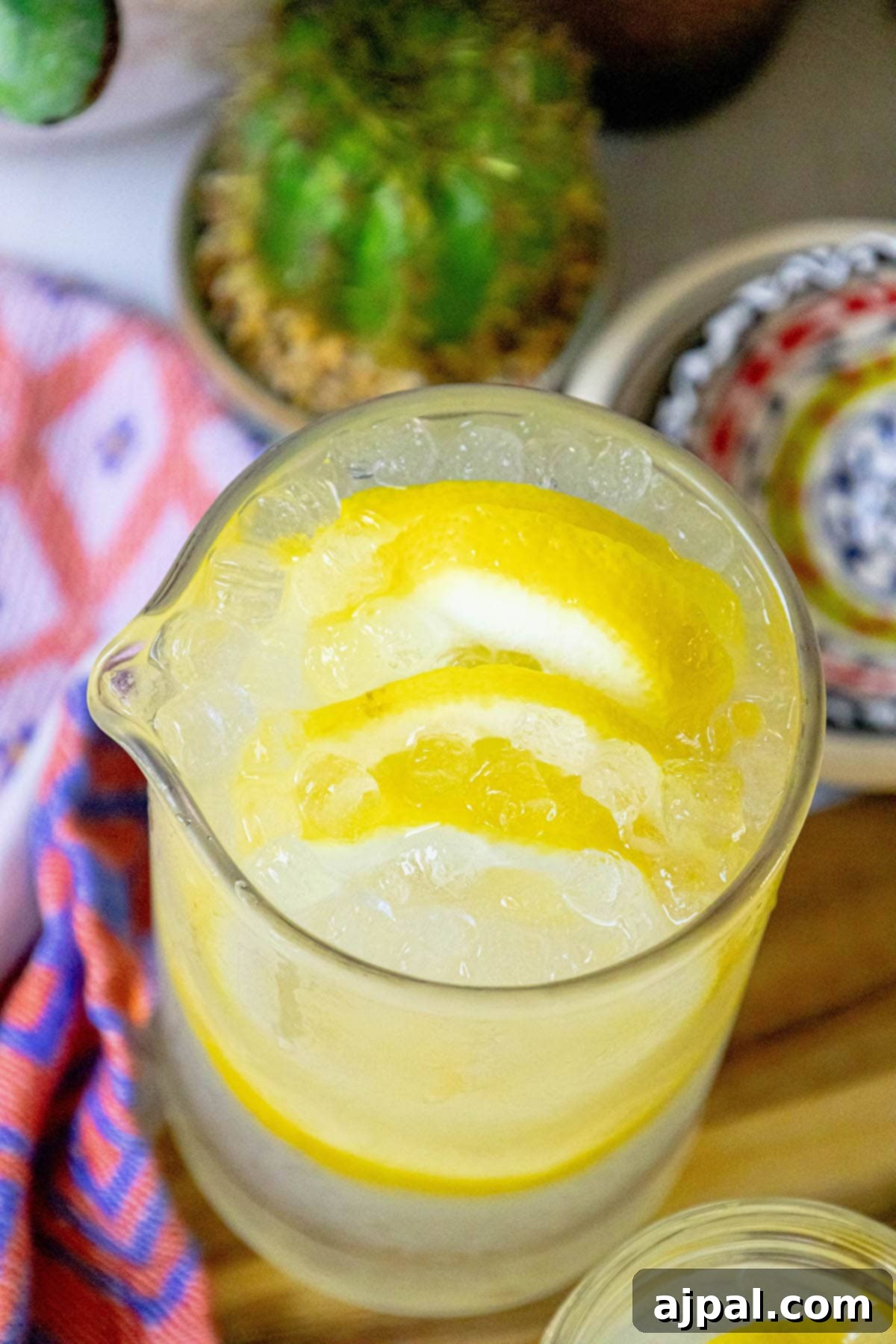A charming pitcher of homemade lemonade, accompanied by fresh lemon slices and a decorative cactus, creating a refreshing and inviting summer scene.