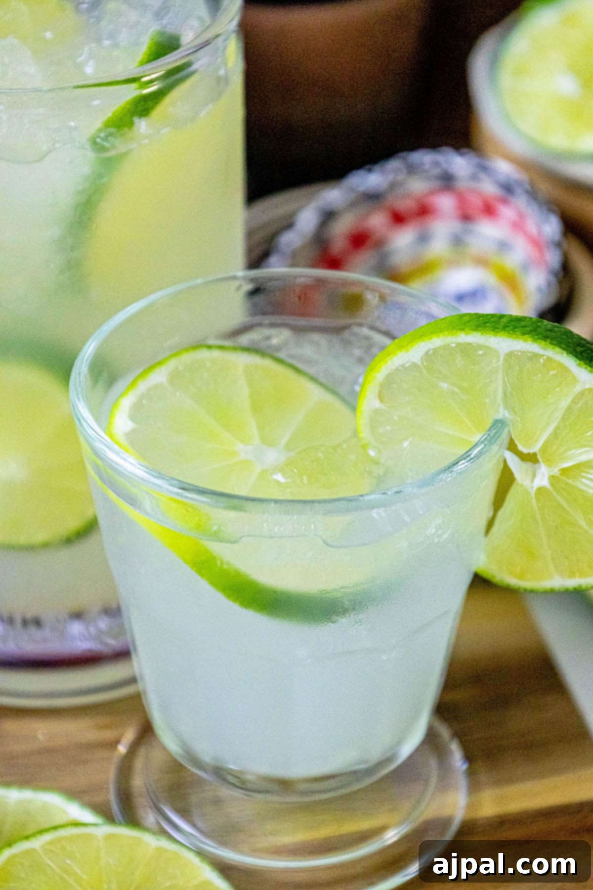 A glass of homemade limeade with ice and sliced limes, ready to refresh.