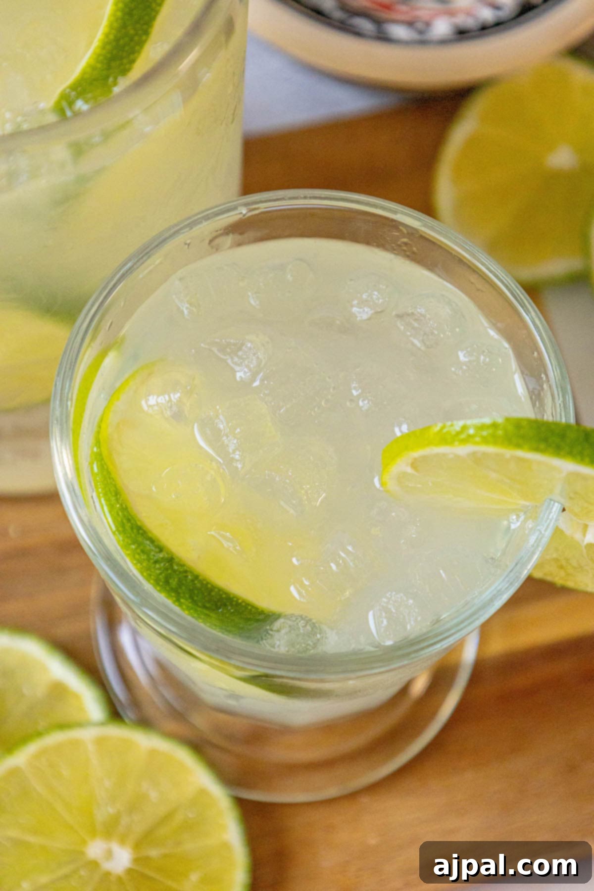 A single glass of homemade limeade with ice and lime slices, inviting a refreshing sip.