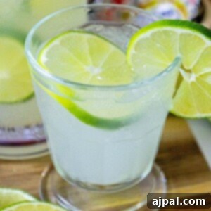 Homemade limeade in a glass with ice and sliced limes for the recipe card.