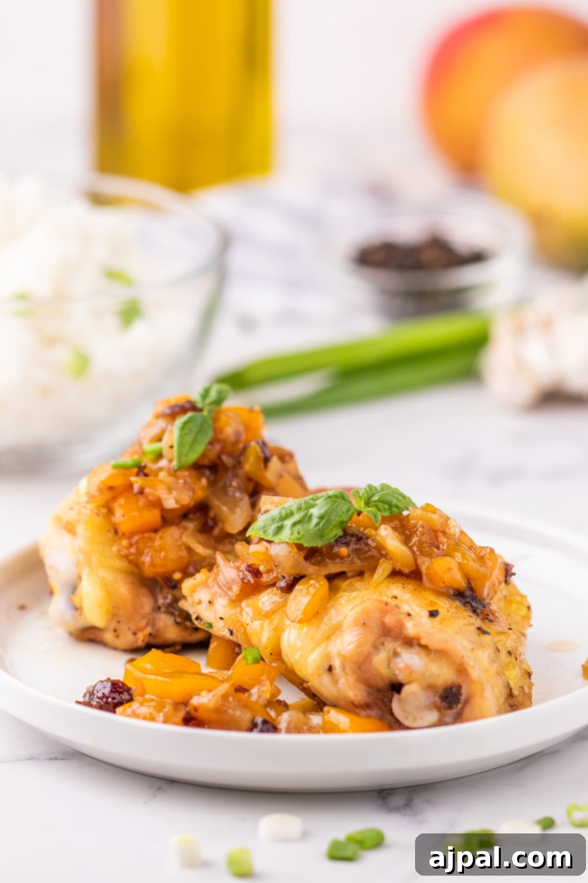 A vibrant plate of chicken thighs generously coated in mango chutney, garnished with fresh green onions, showcasing a delicious and colorful meal.