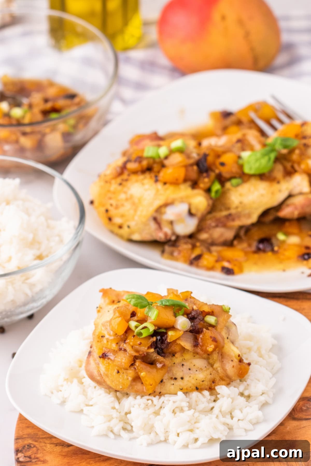 A beautifully arranged plate featuring mango chutney chicken and fluffy white rice, topped with a generous dollop of vibrant mango chutney.
