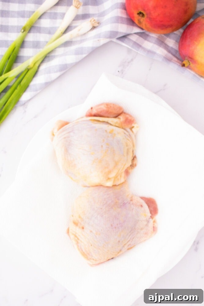 Raw chicken thighs, seasoned and ready for cooking, neatly arranged on a pristine white plate, showcasing their potential for a delicious meal.