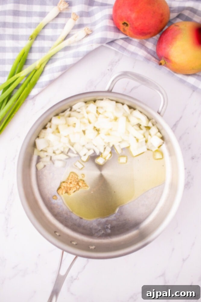 Finely chopped onions and minced garlic are gently sautéing in a hot pan with olive oil, creating an aromatic base for the chutney.