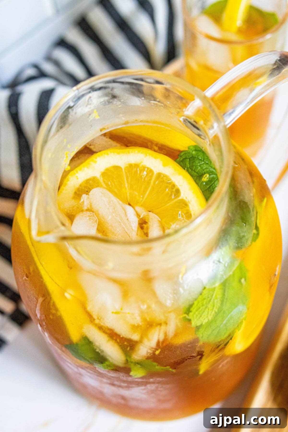Arnold Palmer's Signature Sips 2 A vibrant Arnold Palmer drink in a glass pitcher, garnished with fresh lemon slices and mint leaves, ready to be served over ice. The perfect refreshing beverage for any occasion.