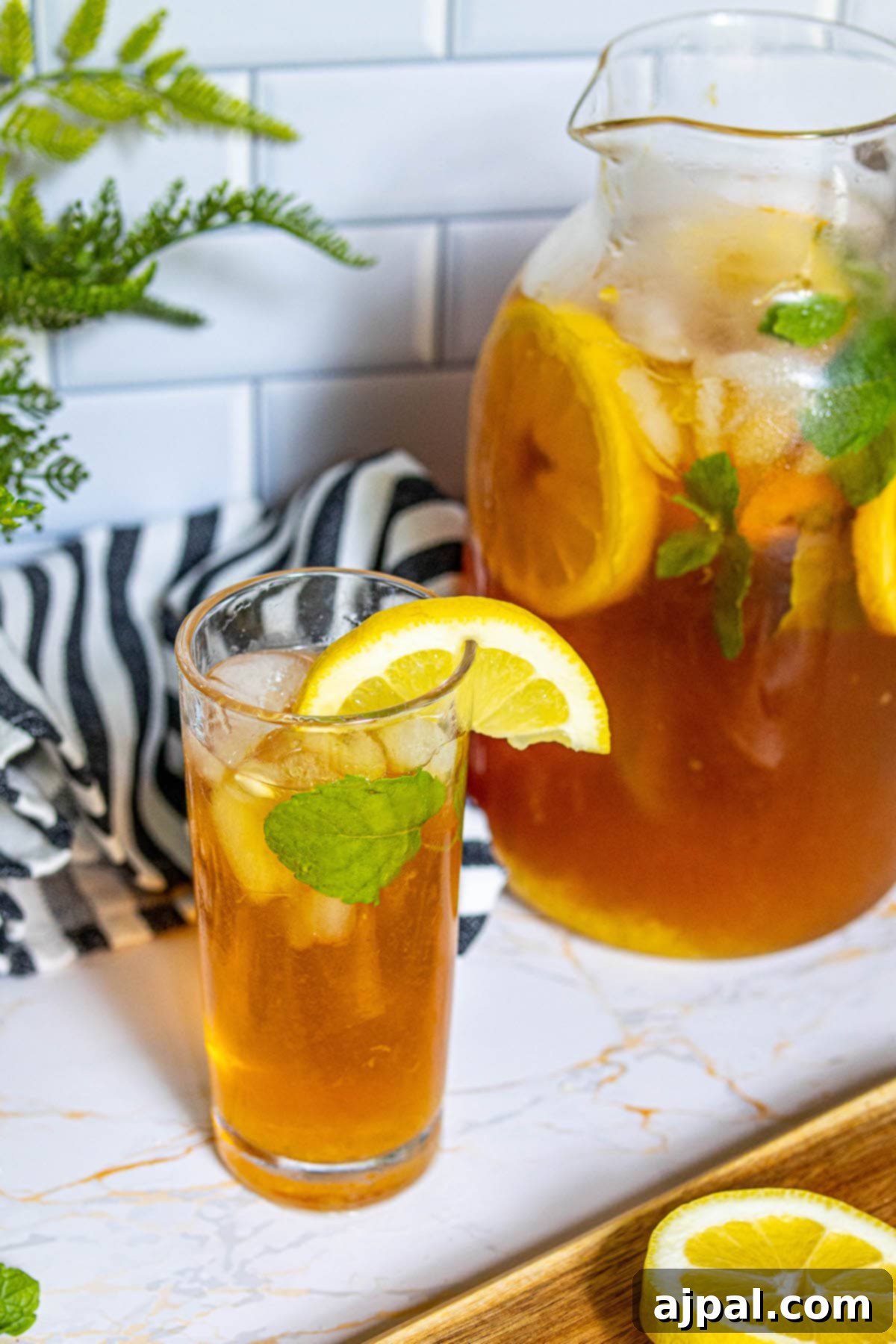 Arnold Palmer's Signature Sips 6 A large glass pitcher filled with an Arnold Palmer, perfectly mixed and garnished with vibrant lemon slices and fresh mint leaves, promising refreshing sips.