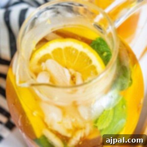 lemonade iced tea arnold palmer in a pitcher with sliced citrus and mint
