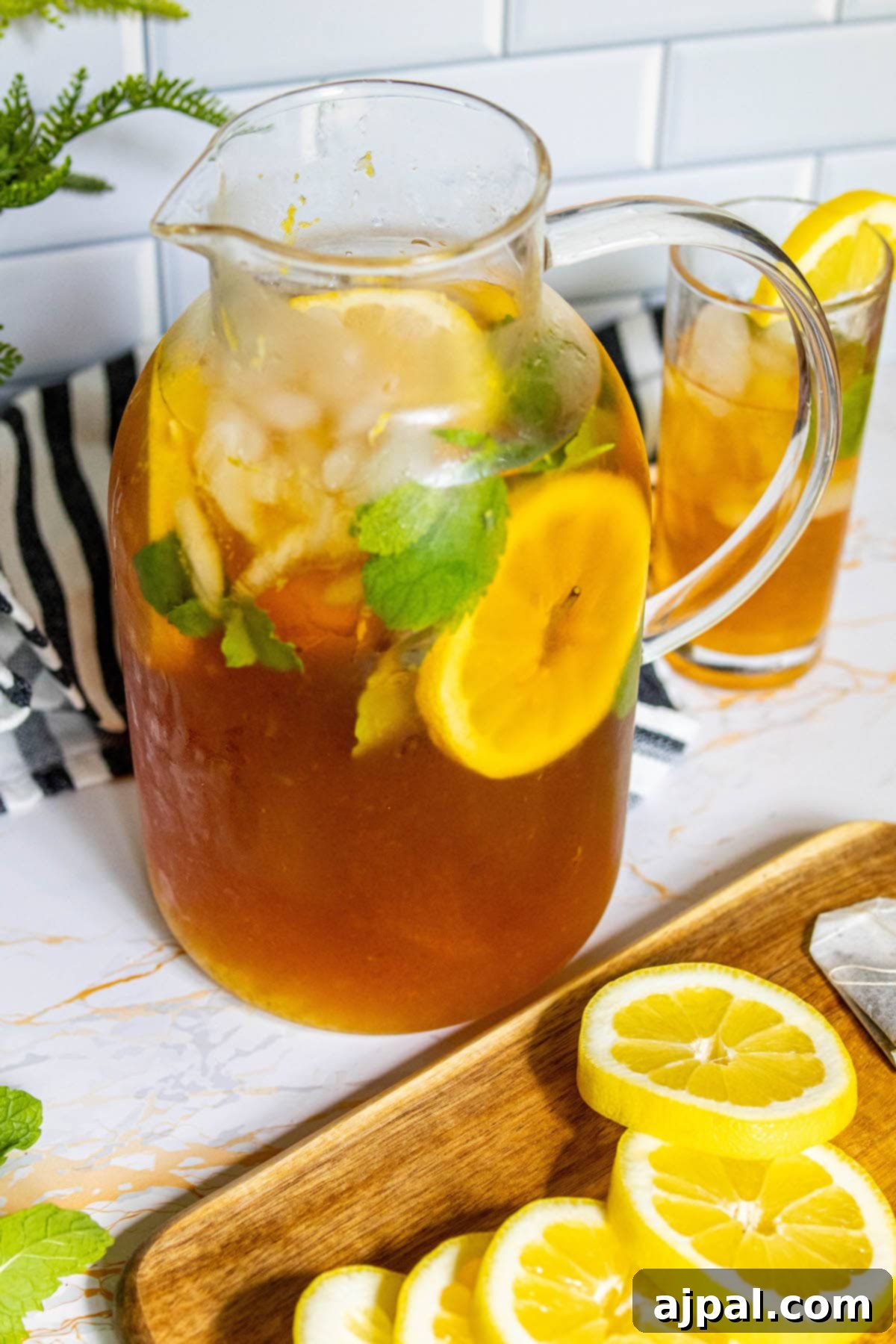 Arnold Palmer's Signature Sips 4 A large pitcher filled with a homemade Arnold Palmer, garnished beautifully with lemon slices and fresh mint, ready to be poured and enjoyed.