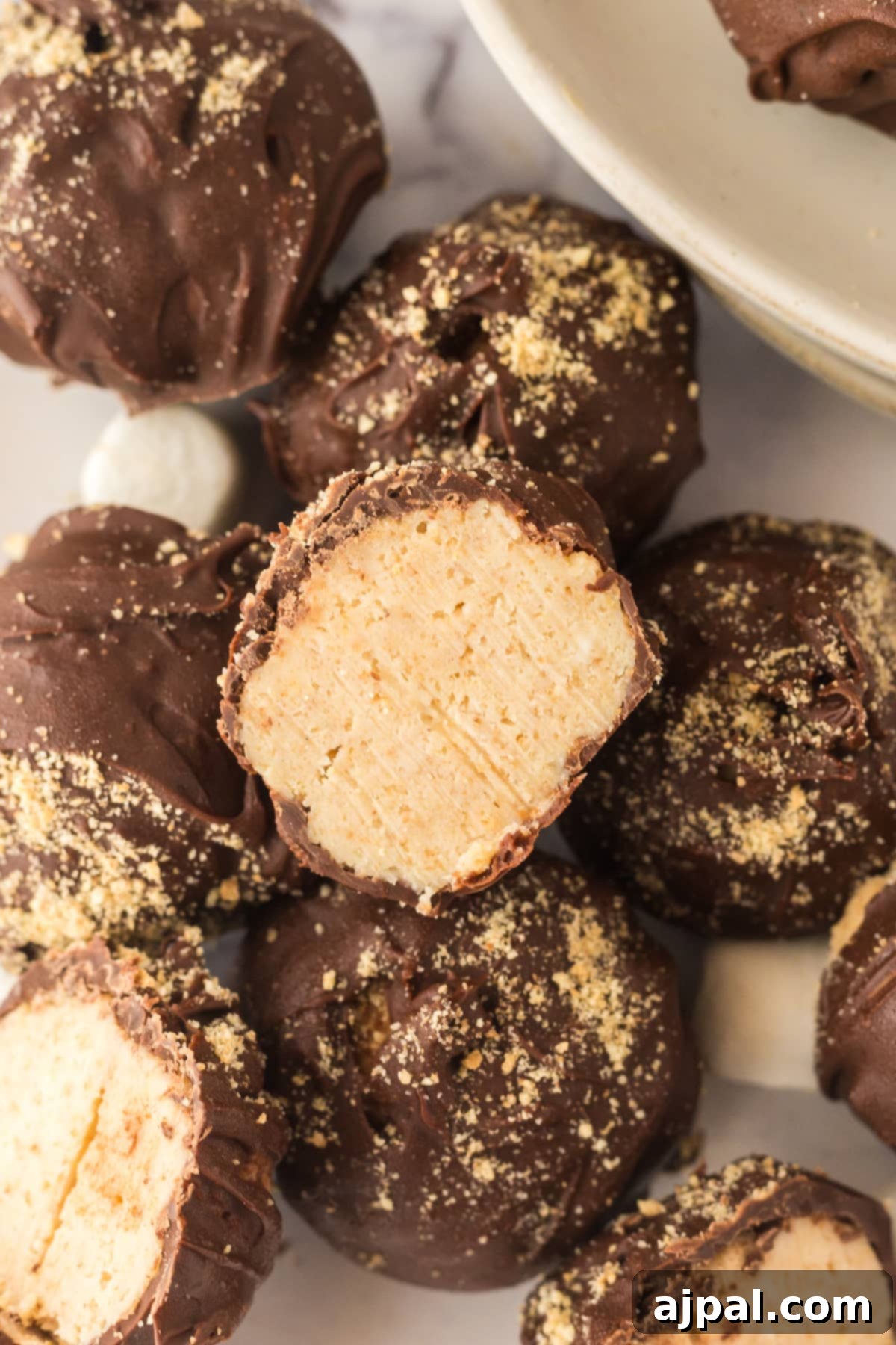 A stack of S'mores truffles with one cut in half, revealing the gooey interior and rich chocolate coating.