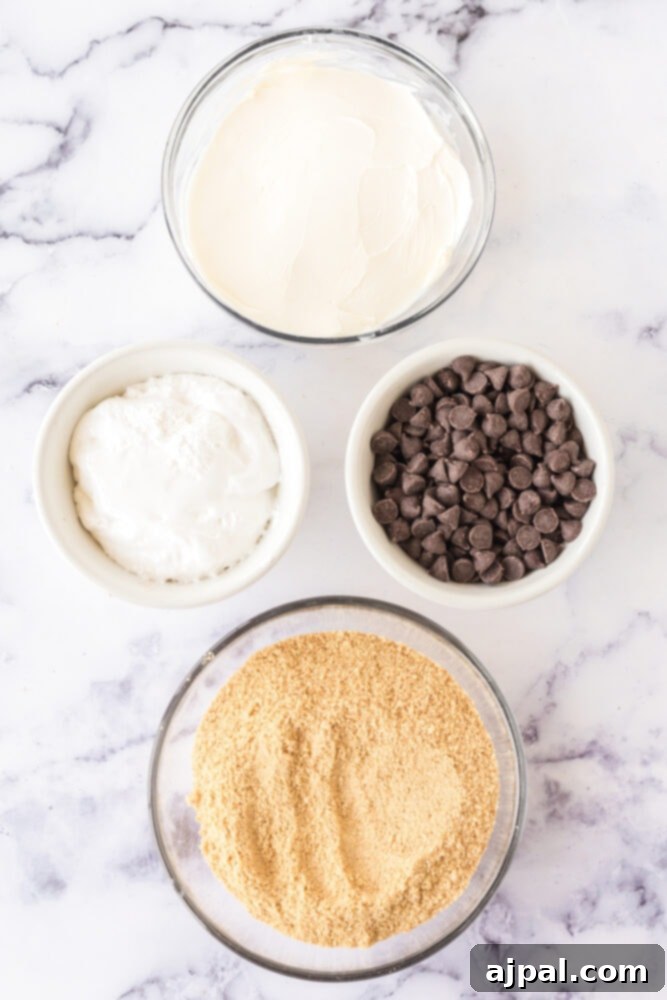 Various S'mores truffle ingredients laid out on a table: marshmallow fluff, graham cracker crumbs, chocolate, and sugar.