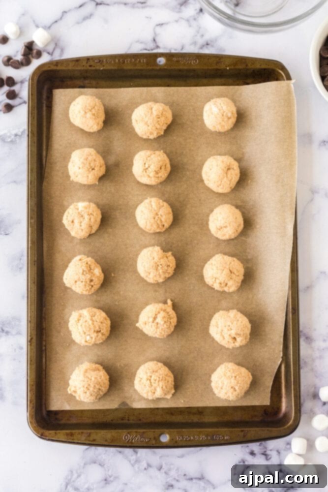 Marshmallow fluff truffles neatly arranged on a baking sheet lined with parchment paper, ready for chilling.