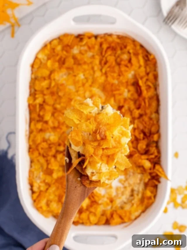 A large baking dish filled with Funeral Potatoes, garnished with fresh herbs, ready to be served.