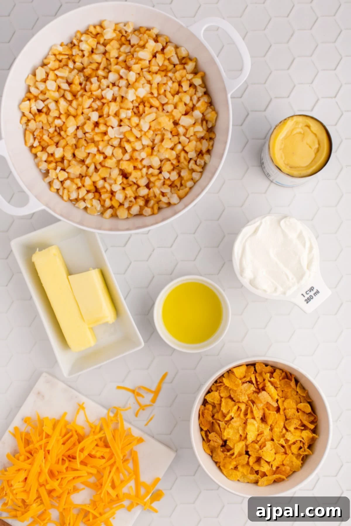 A collection of raw ingredients for funeral potatoes, including frozen potatoes, butter, sour cream, and cheese, arranged on a kitchen counter.