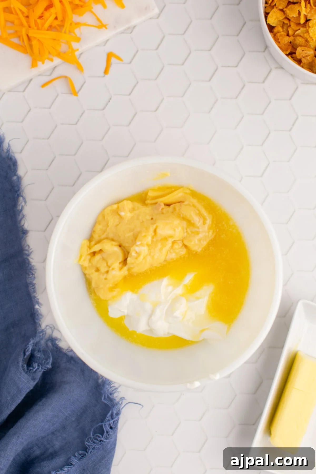A medium bowl containing cream of chicken soup, sour cream, and half of the melted butter, ready to be mixed.