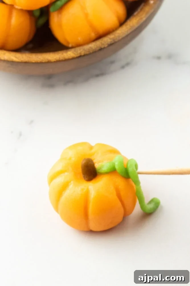 green marzipan shaped into coiled leaf on top of a pumpkin