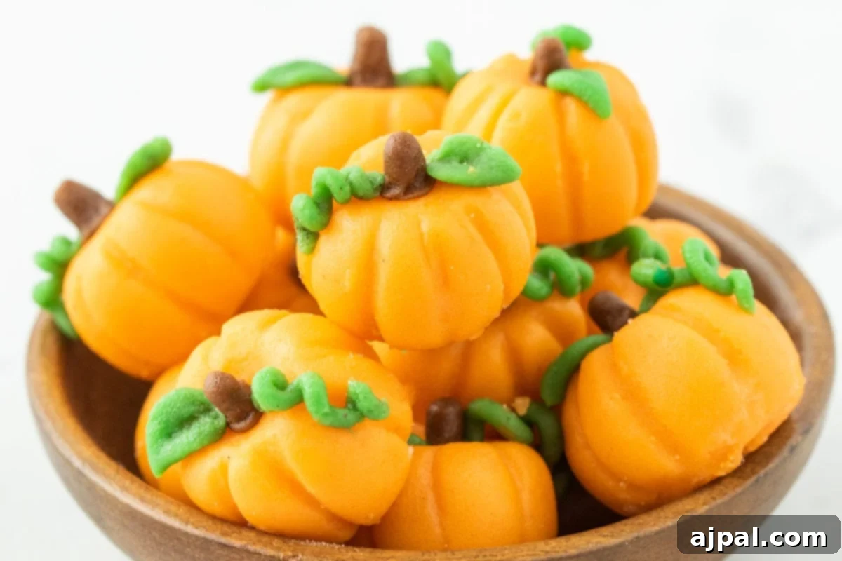 marzipan pumpkins with stem and leaf stacked in a bowl