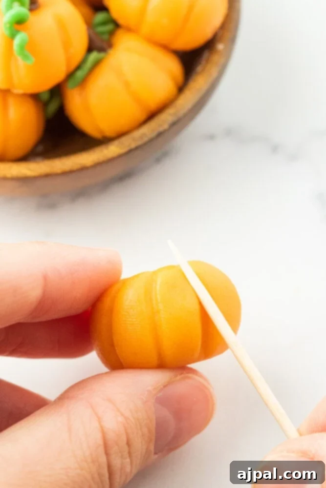 a toothpick pressing a ridge into an orange ball of marzipan