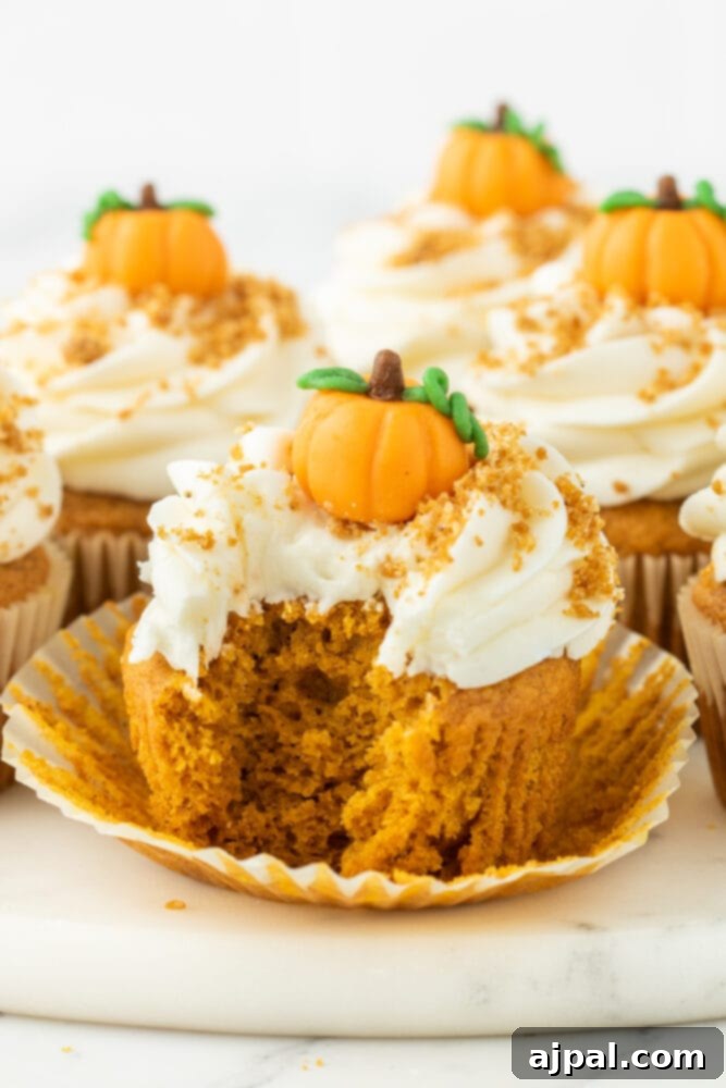 Golden Pumpkin Spice Cupcakes 4 Pumpkin cupcakes with a bite taken, revealing a moist interior.