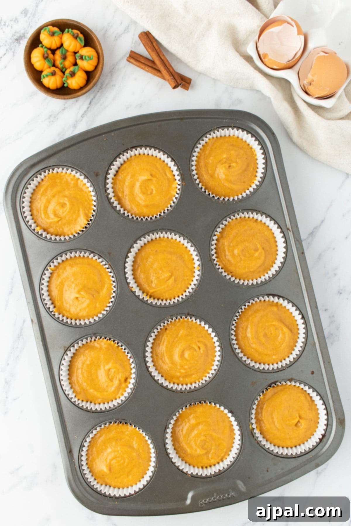 Golden Pumpkin Spice Cupcakes 8 Pumpkin cupcake batter carefully scooped into cupcake liners in a muffin tin.
