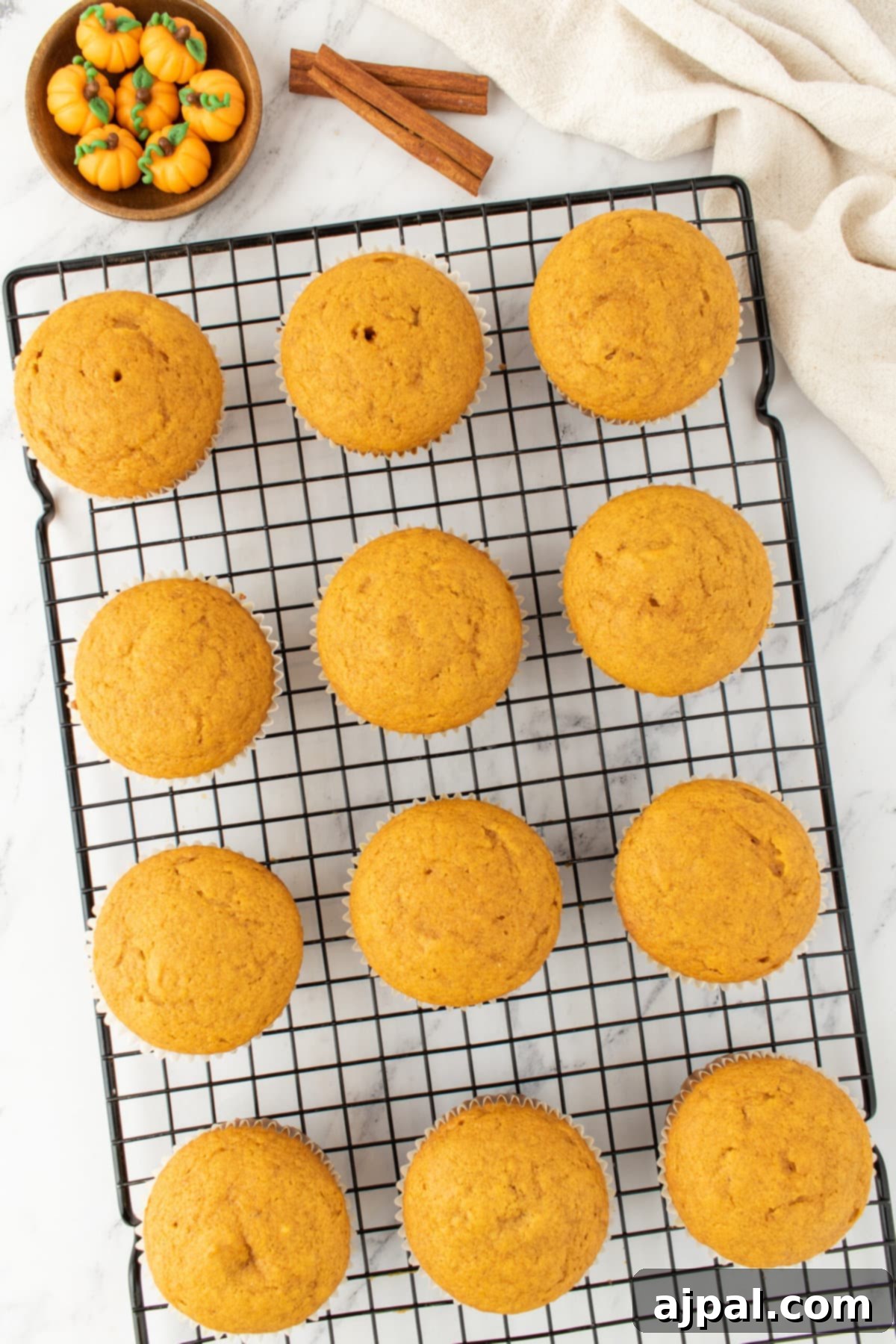 Golden Pumpkin Spice Cupcakes 9 Baked pumpkin cupcakes cooling on a wire rack after being removed from the oven.