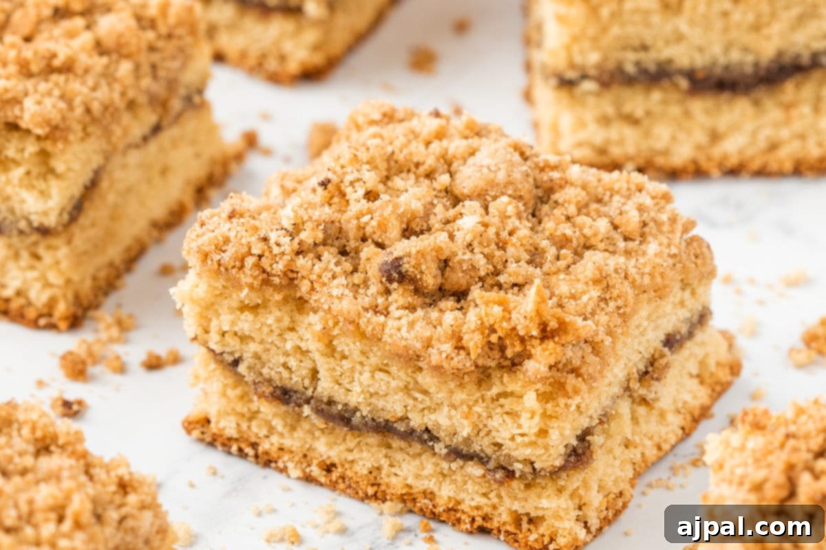 A close-up shot of a single piece of coffee cake, revealing its moist crumb, layered cinnamon filling, and crunchy streusel topping.
