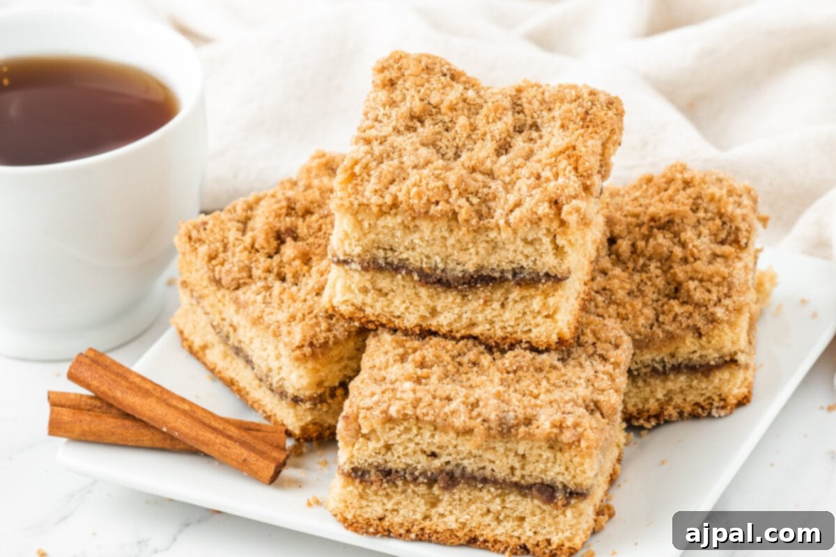 Four golden-brown slices of the best coffee cake resting next to a steaming cup of coffee, inviting you to take a bite.