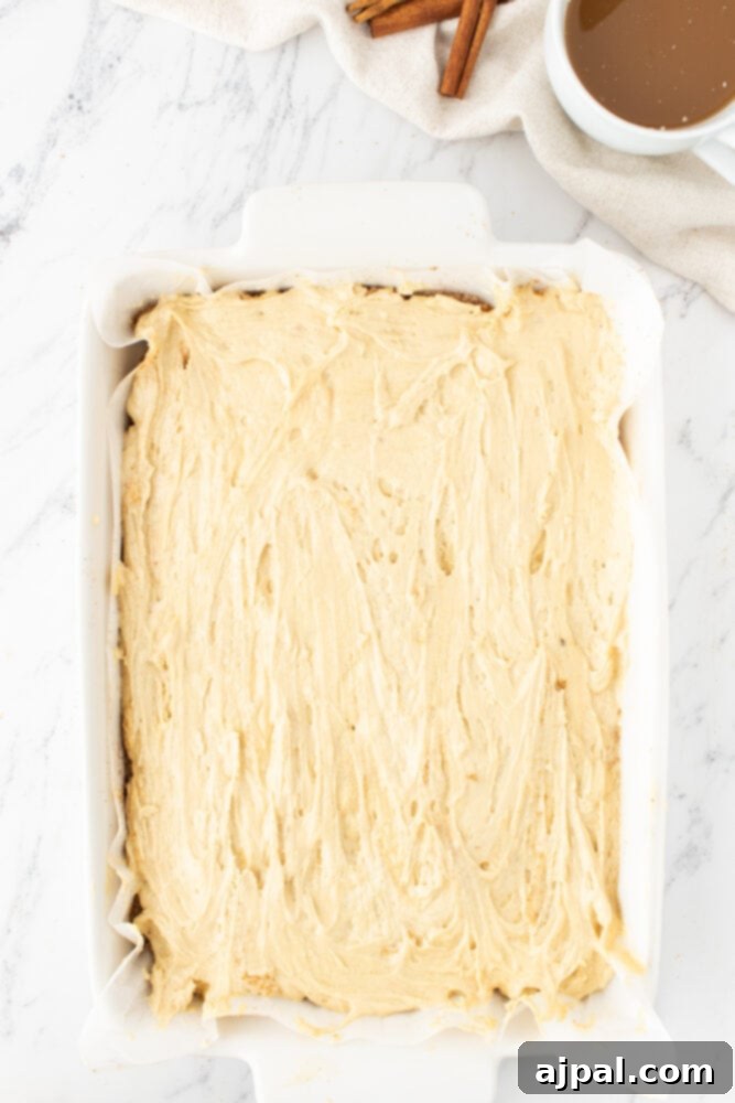 Smooth coffee cake batter evenly spread in a baking dish, forming the first layer of this delicious treat.