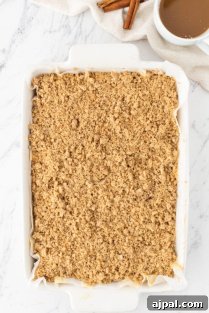 A top-down view of an unbaked coffee cake, generously covered with its streusel topping, ready for the oven.