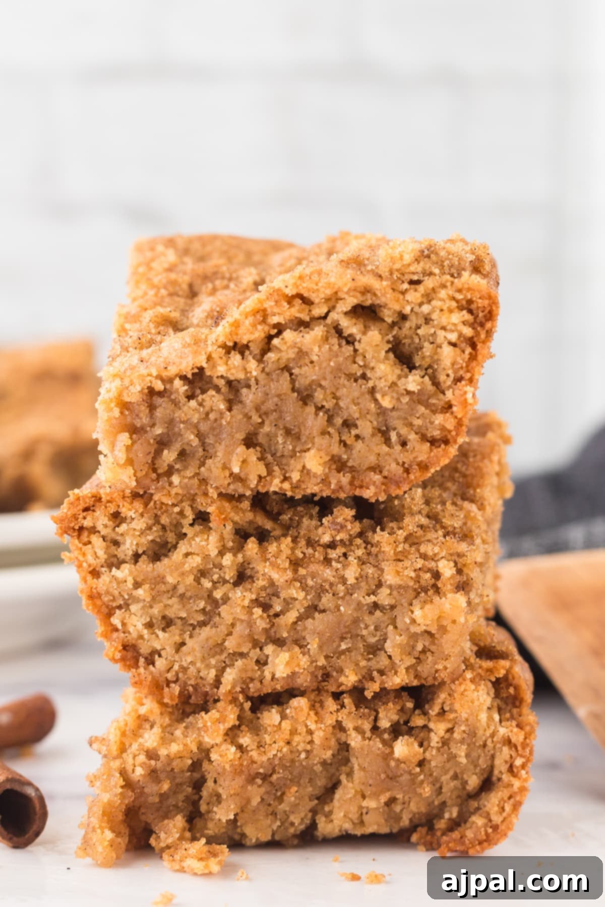 Stacked Snickerdoodle Blondies with a sprinkle of cinnamon on a rustic wooden table