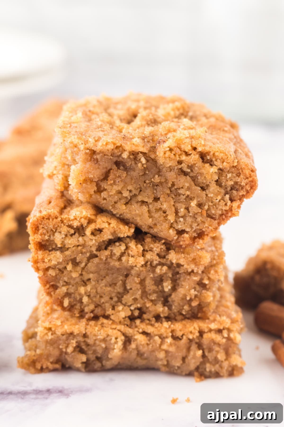A close-up of Snickerdoodle Blondies, sliced and stacked perfectly on a table, highlighting their chewy texture and cinnamon sugar top.