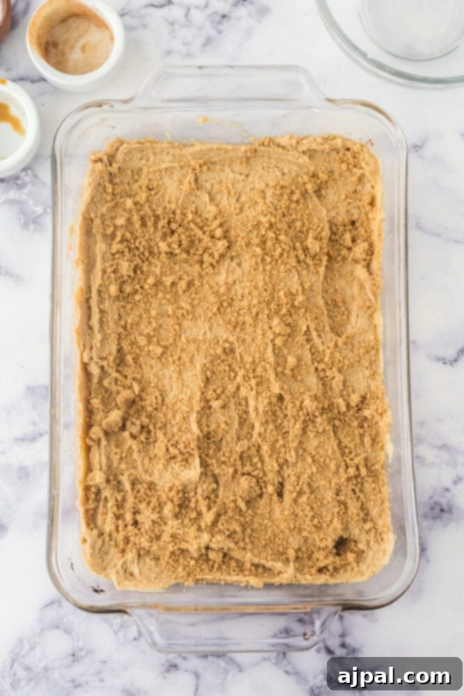 Snickerdoodle blondie batter spread evenly in a casserole dish, topped with cinnamon sugar
