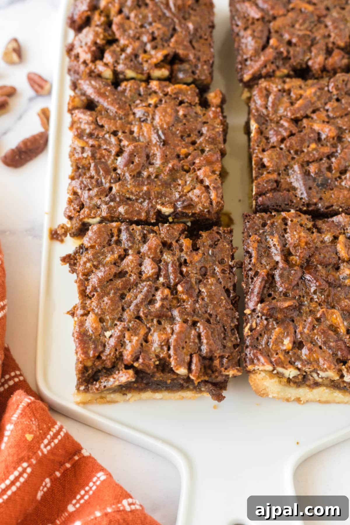 Pecan Pie Bars 11 Pecan pie bars perfectly sliced into squares on a cutting board, ready to be enjoyed.