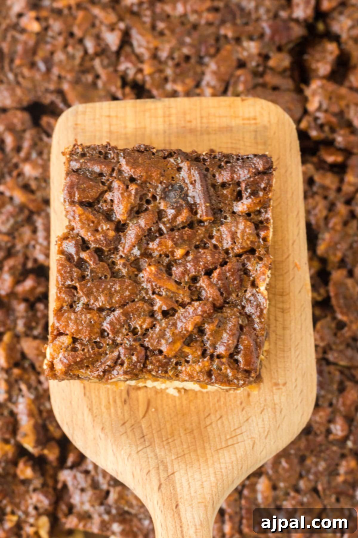 Pecan Pie Bars 4 A single pecan pie bar resting on a spatula, ready to be served, highlighting its rich texture.