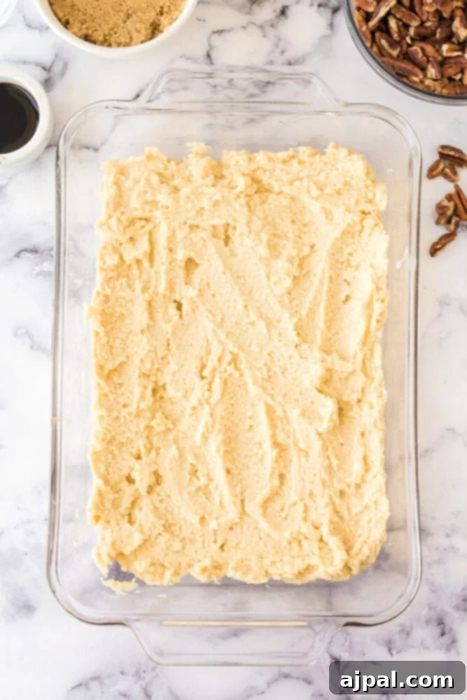 Pecan Pie Bars 7 Pecan pie cookie dough spread evenly in a casserole dish, forming the crust.