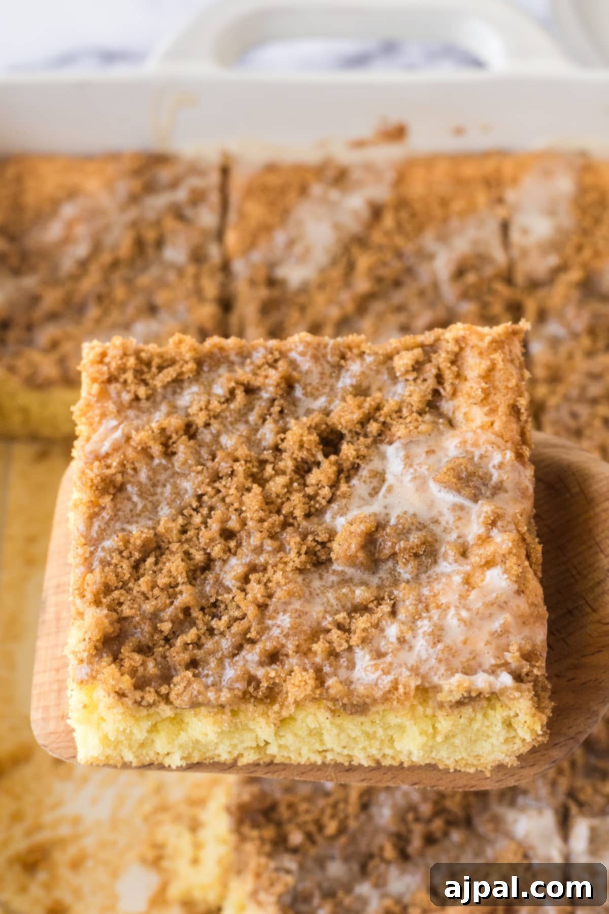 Snickerdoodle Streusel Cake 11 A delectable slice of Snickerdoodle Crumb Cake being lifted from the pan with a spatula, revealing its soft interior and inviting crumbly top.