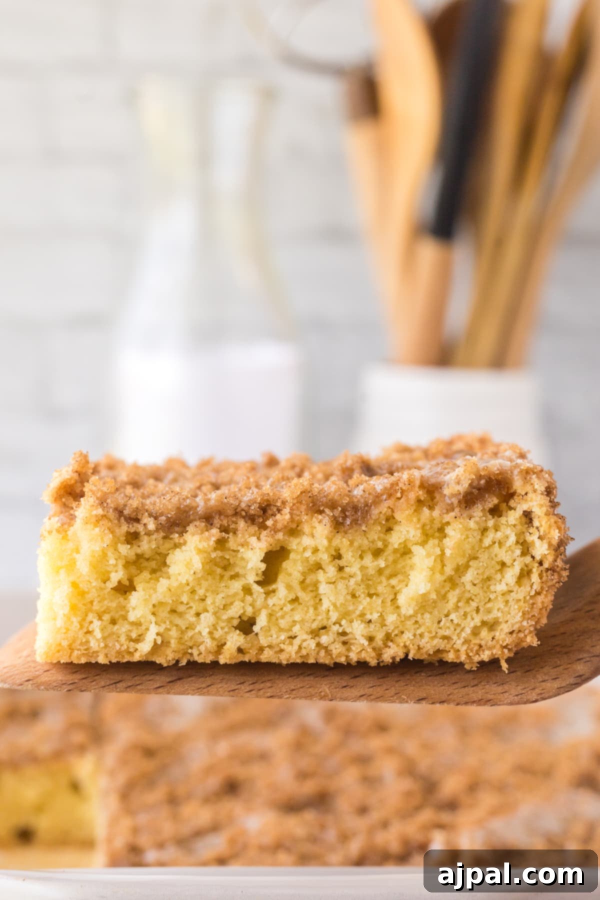 Snickerdoodle Streusel Cake 4 A pristine slice of Snickerdoodle Crumb Cake with its characteristic cinnamon-sugar topping and soft cake layer, presented on a wooden cutting board.