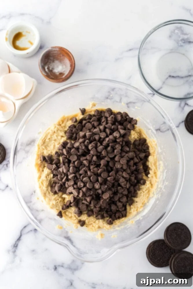 Decadent Oreo Bars 7 Oreo cookie dough in a bowl with eggs and chocolate chips, perfect for making easy cookie bars or oreo stuffed cookies.