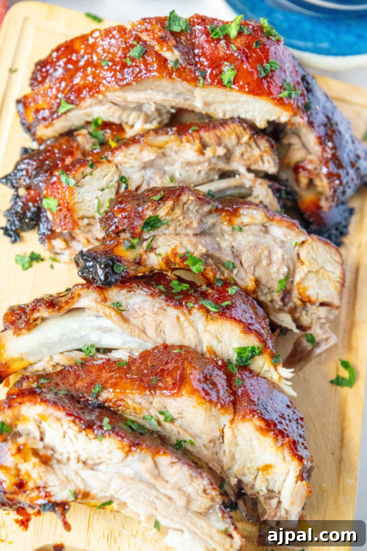 Sweet & Sticky Asian Baked Ribs 9 Sticky Asian baked ribs presented on a wooden cutting board, highlighting the glistening glaze and tender texture, ready for carving.