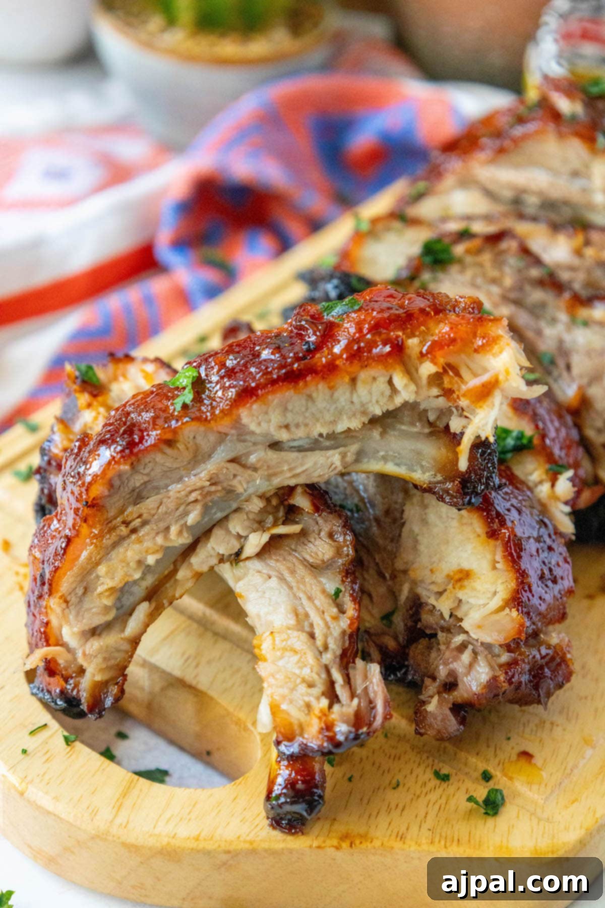 Sweet & Sticky Asian Baked Ribs 7 Beautifully baked Sticky Asian Ribs, cut into individual portions and arranged on a wooden plate, glistening with their sweet and spicy glaze and garnished with fresh green onions.