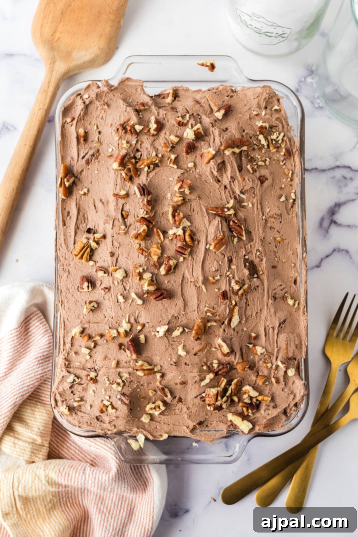 chocolate cake with chocolate icing topped with nuts in a casserole dish on a table