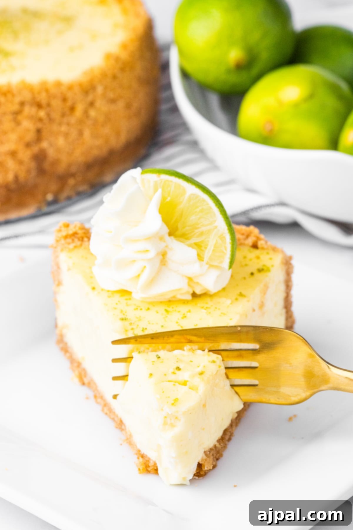 a fork cutting into a slice of key lime cheesecake