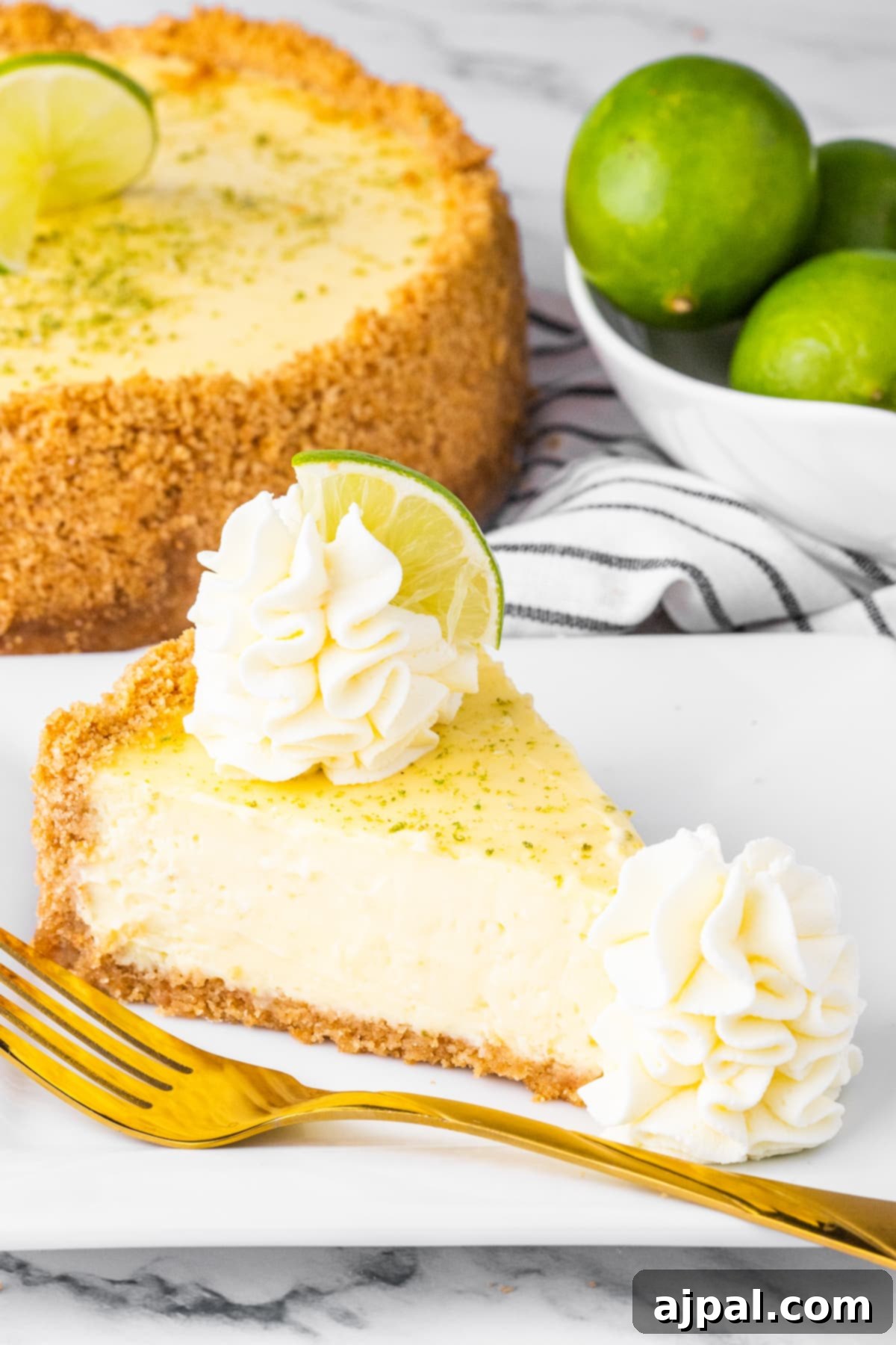 slices of key lime cheesecake on a white plate with whipped cream dollop and a slice of key lime on top
