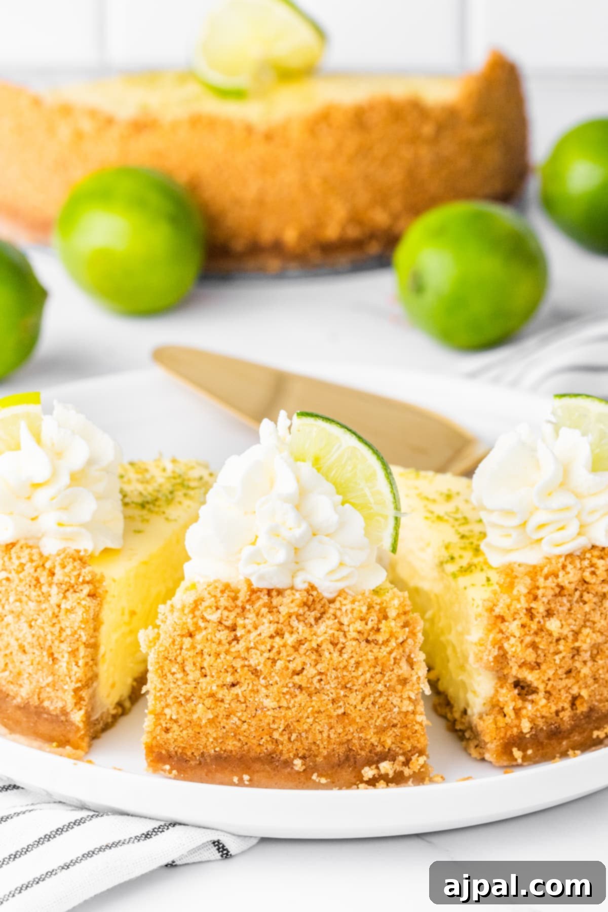 slices of key lime cheesecake on a white plate with whipped cream dollop and a slice of key lime on top