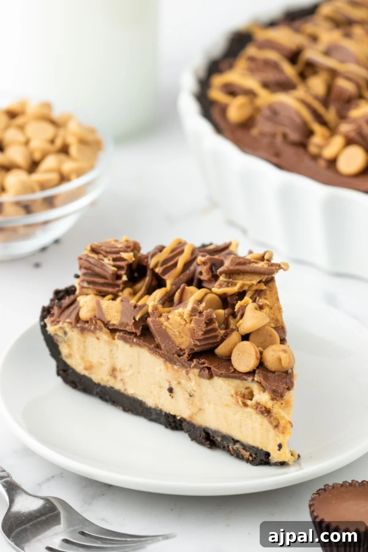 A mouthwatering slice of Reese's Peanut Butter Pie, showcasing its golden peanut butter filling, dark chocolate crust, and decorative mini Reese's cups and peanut butter chips on top.