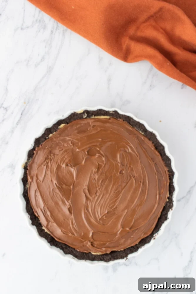 A chocolate pie base with a perfectly spread layer of milk chocolate ganache, awaiting its final toppings.