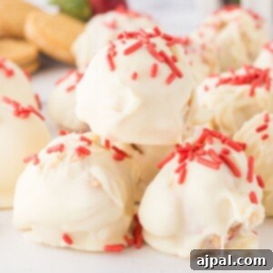 A stack of strawberry shortcake truffles dipped in white chocolate with pink sprinkles on top